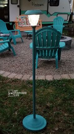 a blue chair sitting in the middle of a gravel area next to a camper