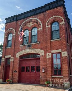 an old brick building with two red doors and american flag on the top of it