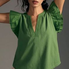 a woman wearing a green top with ruffled sleeves