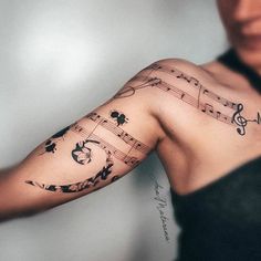 a woman's arm with musical notes and flowers on the left side of her arm