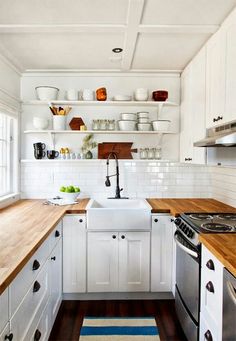 the kitchen is clean and ready for us to use it's white cabinets, wood counter tops, and dishwasher