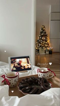 a table topped with coffee cups and donuts next to a laptop on top of a bed