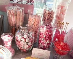 there are many different types of candies on display in glass vases and jars