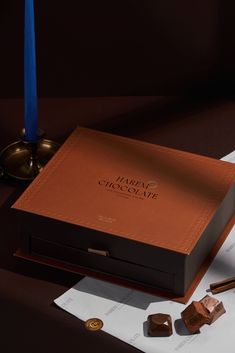 a chocolate box sitting on top of a table next to a candle and some pieces of paper