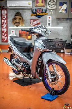 a motorcycle parked inside of a garage on top of a wooden floor next to a blue mat