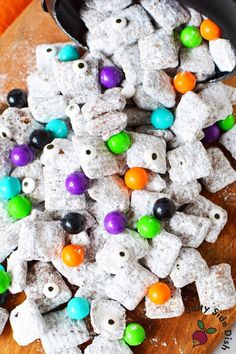 a wooden cutting board topped with lots of white dog treats covered in colorful candies