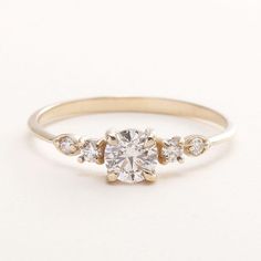 an engagement ring with three stones on the side and a round diamond in the middle