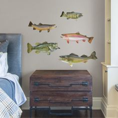 three fish are hanging on the wall next to a dresser and bed in a bedroom