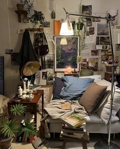 a living room filled with lots of furniture and plants on the wall above it is a couch covered in pillows