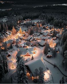 an aerial view of a village at night with christmas lights on trees and snow covered ground