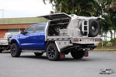 a blue pick up truck is parked in front of a building with its doors open