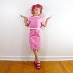 a woman in pink dress standing on wooden floor with arms outstretched and hands out to the side