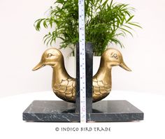 a golden duck statue sitting on top of a table next to a potted plant