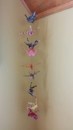 a group of origami birds hanging from a string on a wall in a room