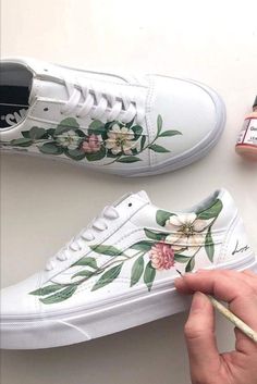 someone is painting flowers on their white shoes