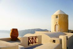 a large brown vase sitting on top of a white building with mountains in the background