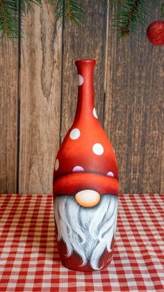 a red and white vase sitting on top of a table next to a christmas tree