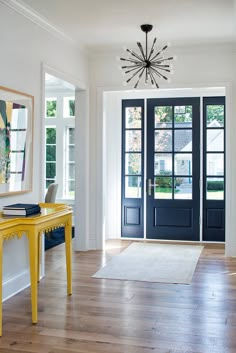 the front door is open and there are two yellow tables in front of it, along with