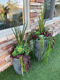 two large planters sitting on the side of a brick building next to a window