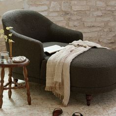 a chair with a blanket on it next to a small table and some shoes in the room