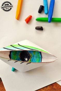 an origami bird made out of colored crayons on top of paper