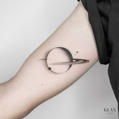 a small saturn tattoo on the arm