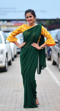 a woman in a green sari posing for the camera with her hands on her hips