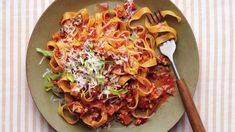 a plate full of pasta with sauce and parmesan cheese on top, next to a fork