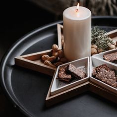 a candle is lit in the middle of four square trays with crackers and nuts