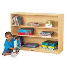 a young boy sitting in front of a book shelf