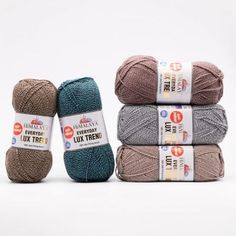 four balls of yarn sitting next to each other on a white surface with the labels in front of them