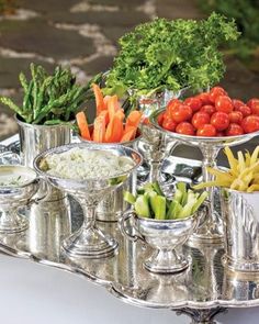 a silver tray filled with assorted vegetables and dips on top of a table