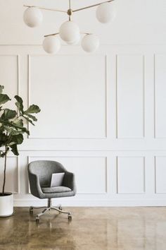 a room with a chair, potted plant and wall lights on the ceiling above it