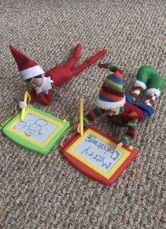 three elfs are laying on the floor with their writing instruments and markers in front of them