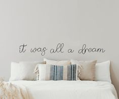 there is a bed with pillows on it and a wall that says it was all a dream