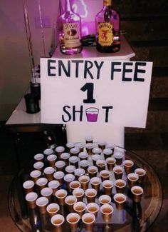 there is a sign that says entry fee 1 shot on the table with cups in front of it