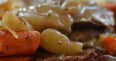 a close up view of some meat and potatoes on a plate with gravy