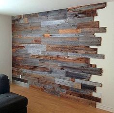 a living room with a black couch and wooden wall