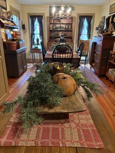 a wooden table topped with a vase filled with greenery next to a candle holder