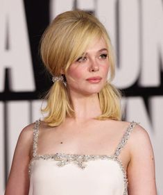 a woman with blonde hair wearing a white dress and diamond earrings on her head, looking off to the side