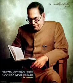 a man sitting in a chair holding an open book and looking at the camera while wearing glasses