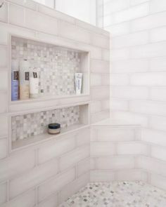 a white tiled bathroom with shelves on the wall