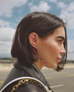 a woman with ear piercings on her ears is standing in front of an airport runway