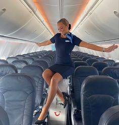 a woman sitting on the back of an airplane with her arms out and legs crossed