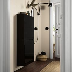 an open door leading to a bathroom with a black cabinet next to it and a plant in the corner