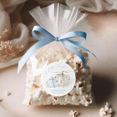 a bag filled with white popcorn sitting on top of a table next to some flowers