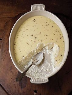 a white bowl filled with soup on top of a wooden table next to a spoon