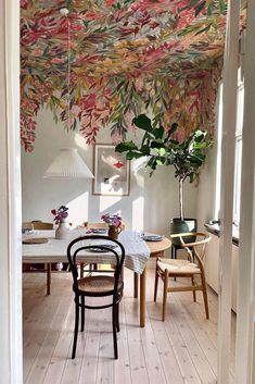 an open door leading to a dining room with floral wallpaper on the ceiling and wooden flooring