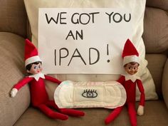 two elfs sitting on a couch with a sign that says we got you an ipad