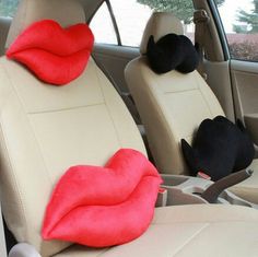 two black and white cats sitting in the back seat of a car with red lips on them